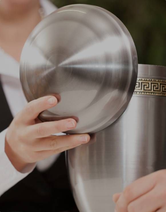Hands holding a shiny metal bowl and cup with a gold decorative band
