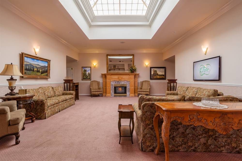 Spacious living room with tan sofas, fireplace, skylight, and patterned rug
