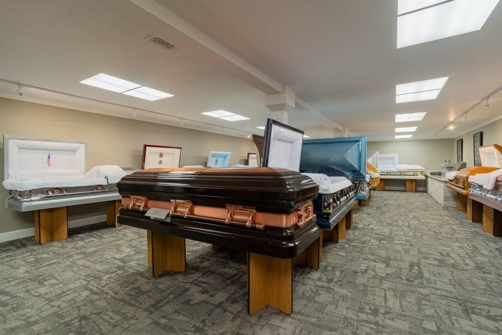 Showroom with several mattresses on display under bright ceiling lights and carpeted floor