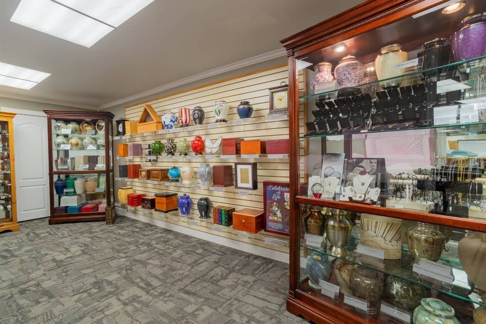 Bright showroom aisle with glass display cabinets and colorful glassware on wall shelves.