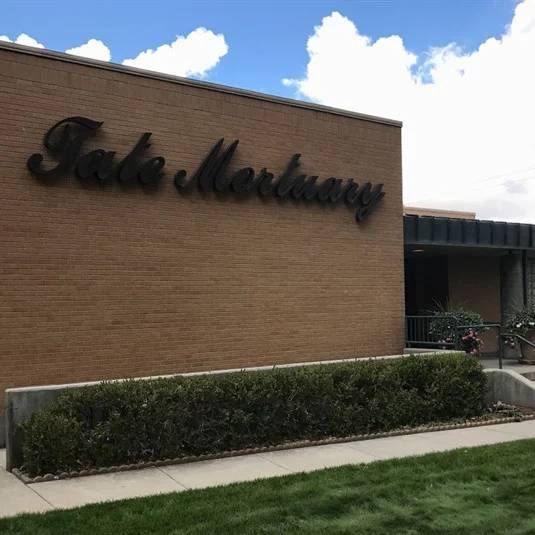 Facade of TaleMedway building with brick wall, black sign, shrubs, and cloudy sky