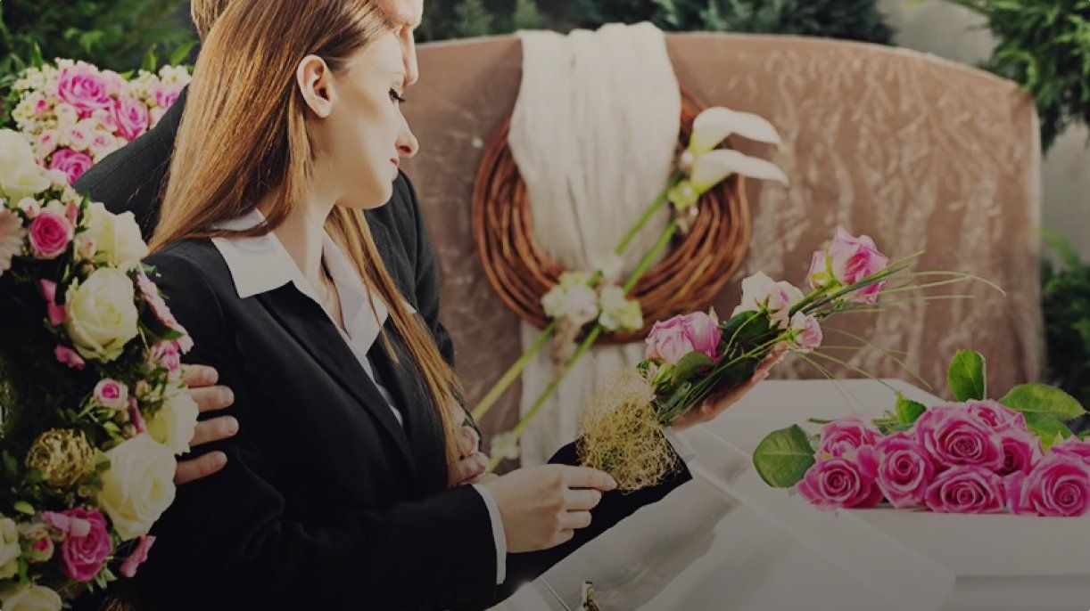 Woman arranging pink flowers at a table with bouquets and floral decorations in the background