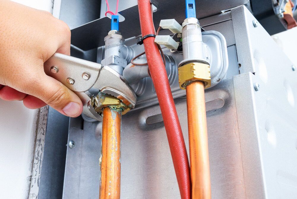 A Person Is Fixing A Water Heater With A Wrench — Panorama Plumbing In Dubbo, NSW