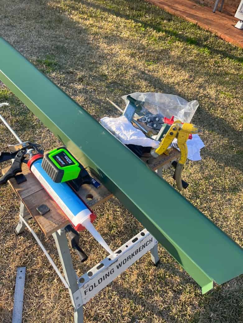 A Green Piece Of Metal Is Sitting On Top Of A Wooden Workbench — Panorama Plumbing In Dubbo, NSW