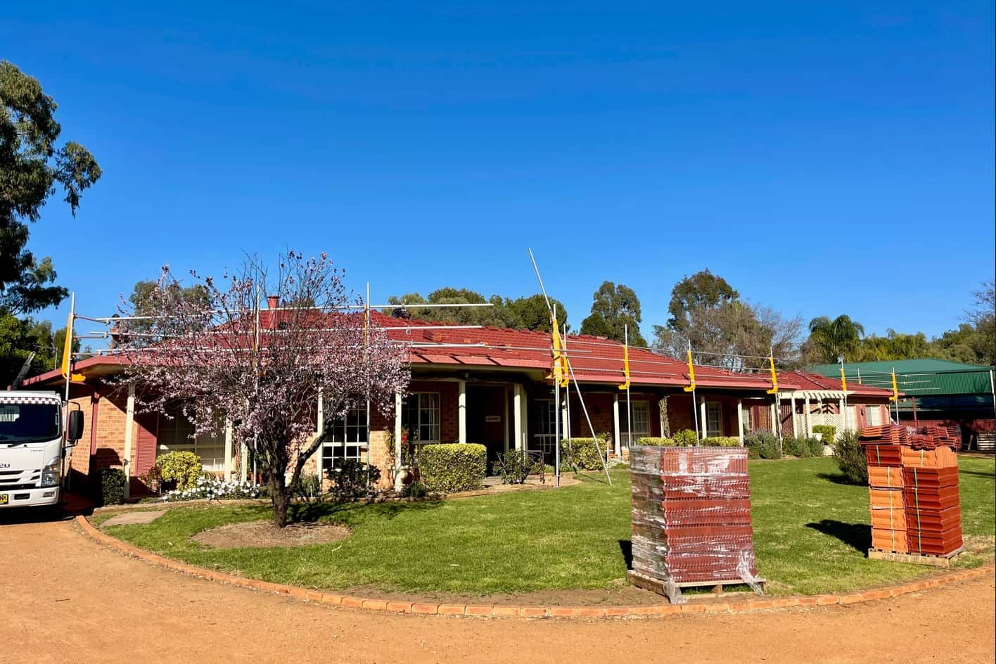 A Large House With A Red Roof And A Truck Parked In Front Of It — Panorama Plumbing In Wellington, NSW