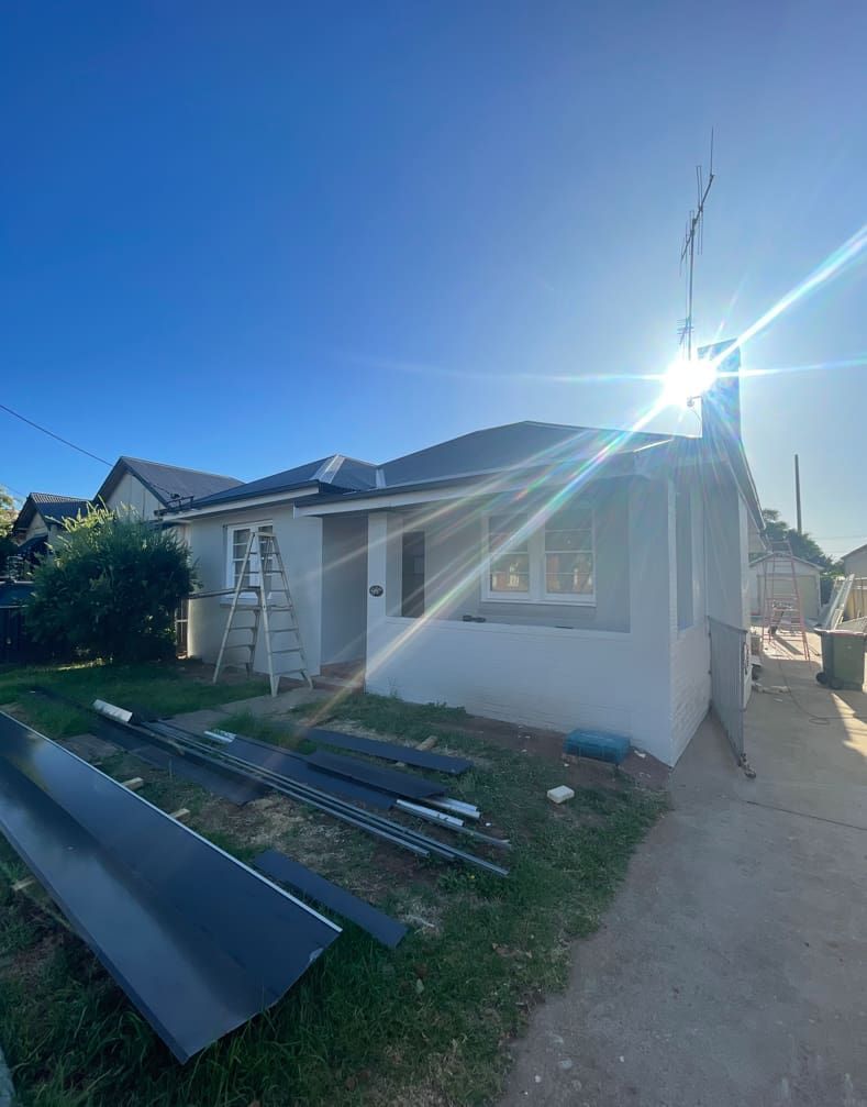 A White House With A Ladder In Front Of It Is Being Remodeled — Panorama Plumbing In Wellington, NSW