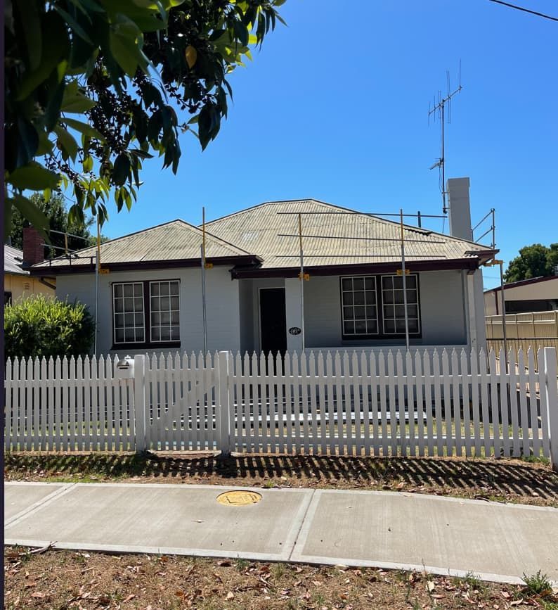 A Small White House With A White Picket Fence Around It — Panorama Plumbing In Dubbo, NSW