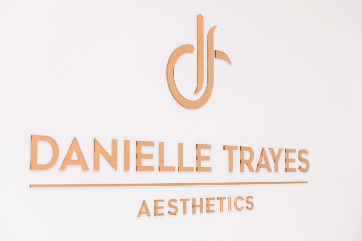 The logo for danielle trayes aesthetics is on a white wall