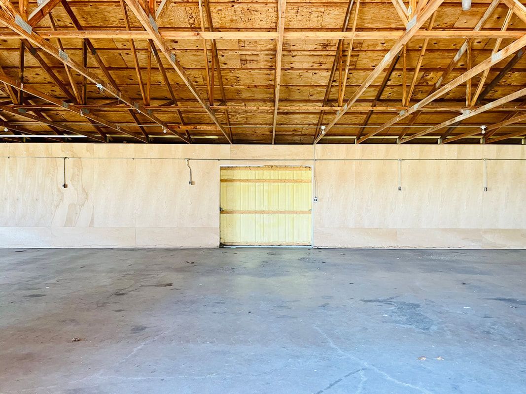 An empty garage with a yellow door and a wooden ceiling.