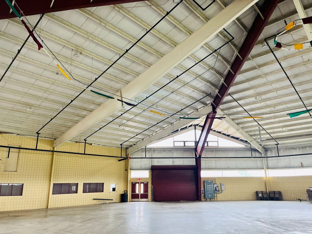 A large empty warehouse with a red door and a white ceiling.