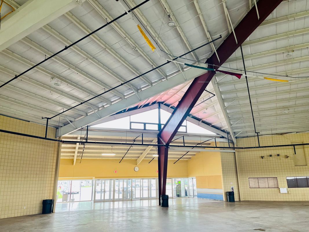 A large empty room with a ceiling fan hanging from the ceiling.