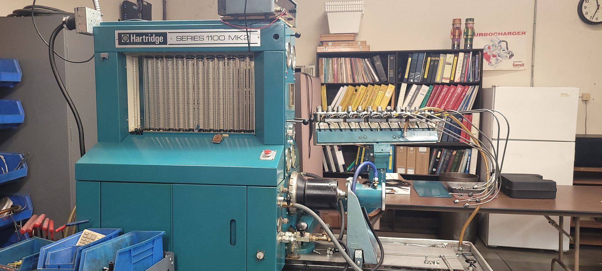 Blue industrial machine in a workshop, with tools, shelves, and a workbench nearby