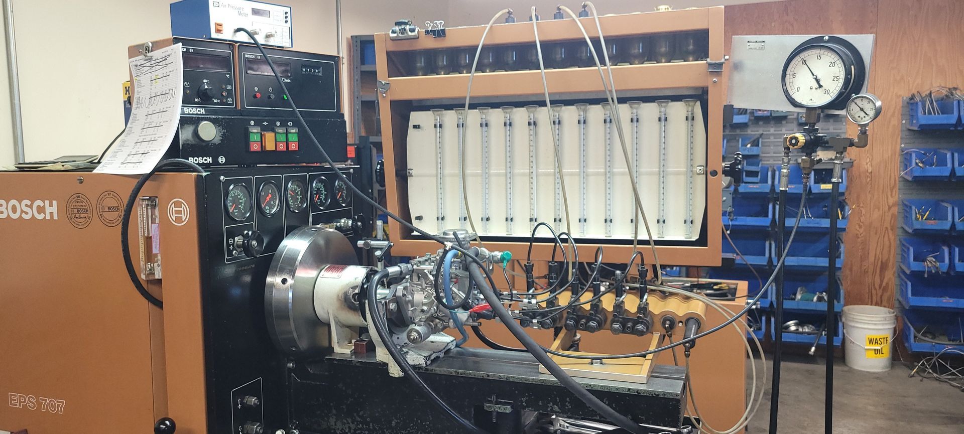 Industrial test bench with a Bosch engine setup, gauges, and wiring in a workshop.