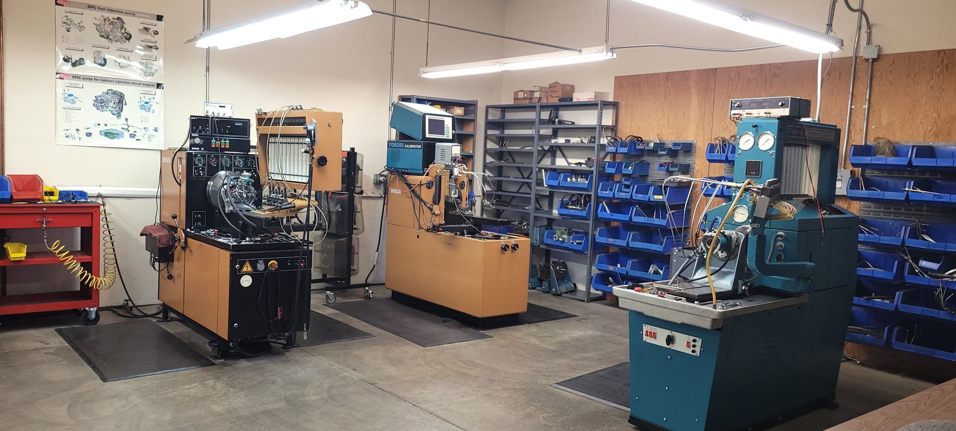 Garage workshop with workbenches, tools, and organized shelves of parts on a concrete floor.