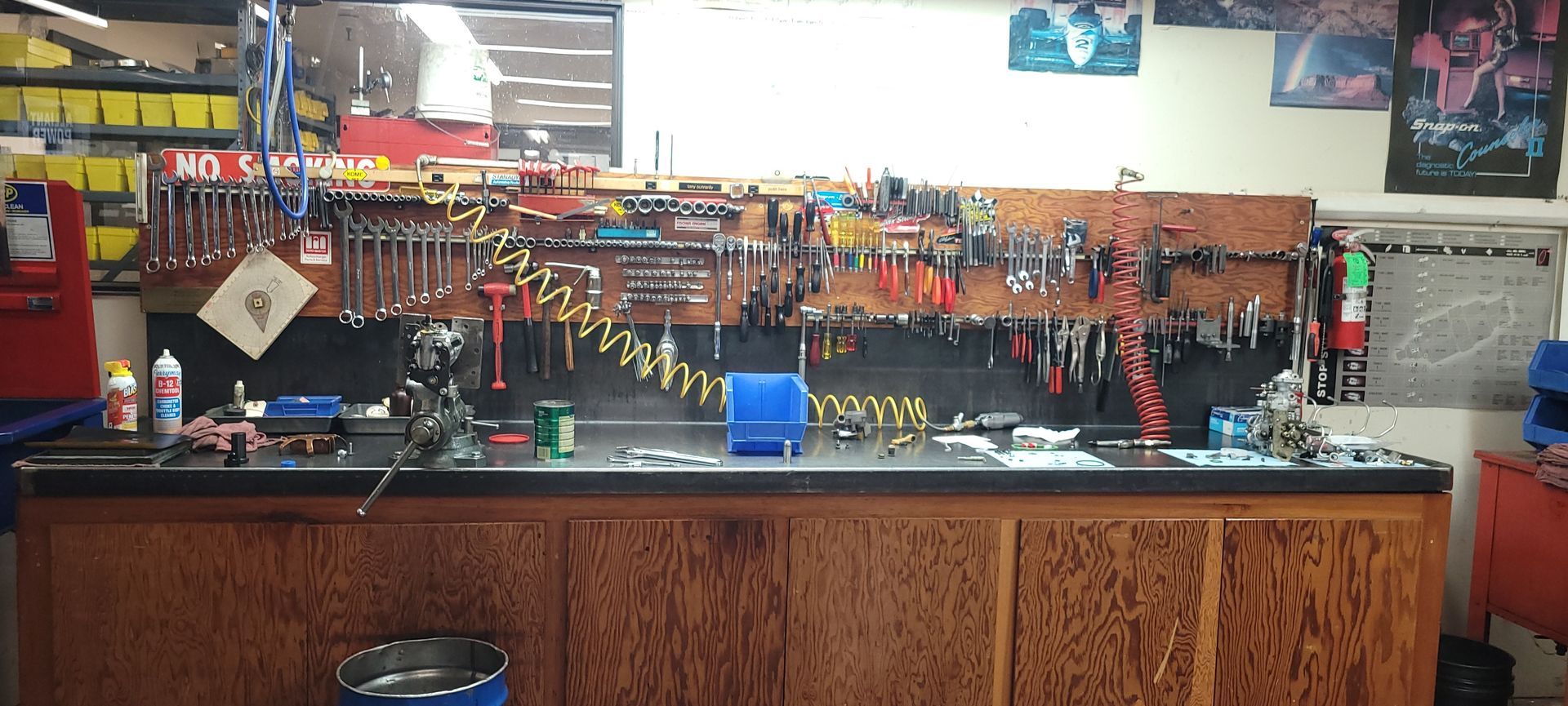 Cluttered workbench with hanging tools and supplies in a workshop garage