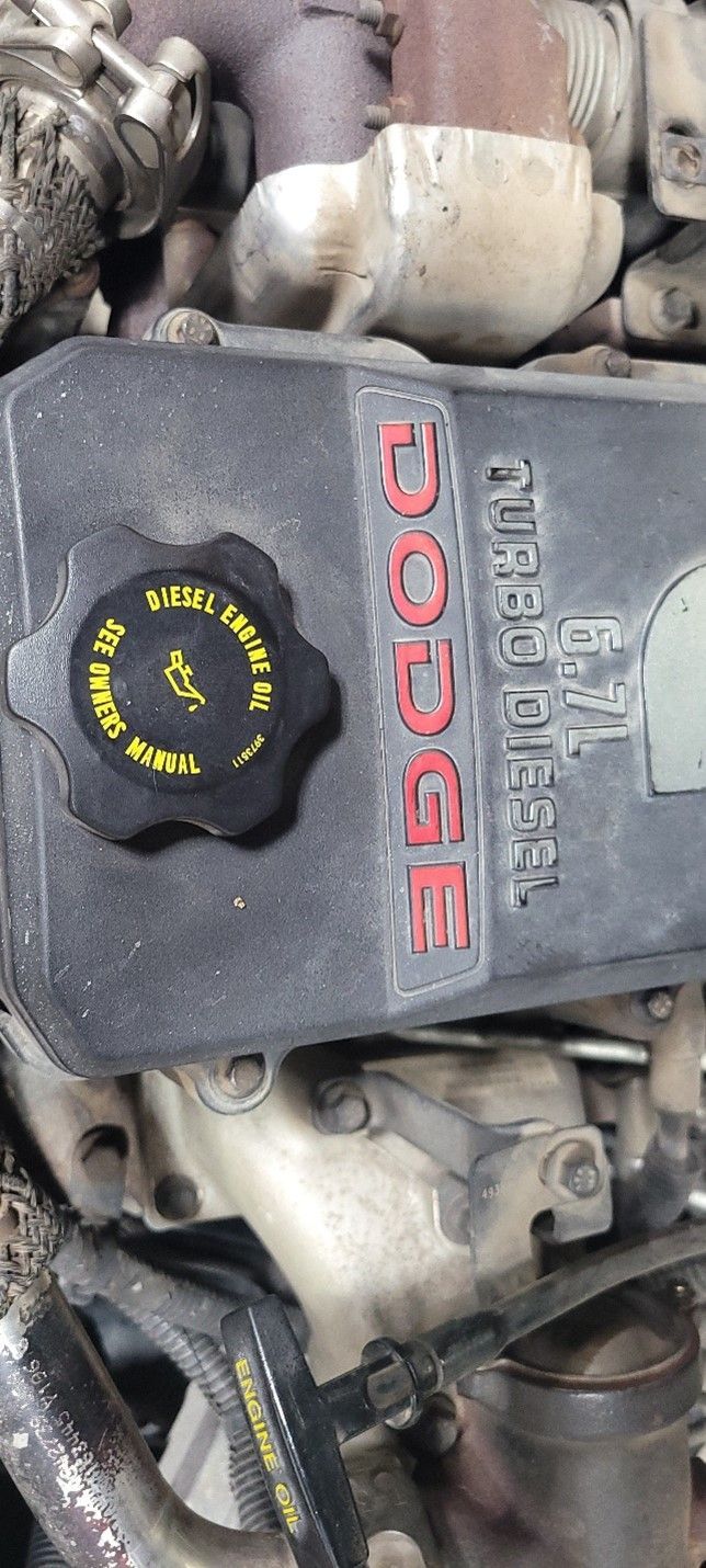 Close-up of a Dodge engine cover with a black oil cap and red logo.