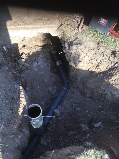 A drain pipe is being installed in a hole in the ground