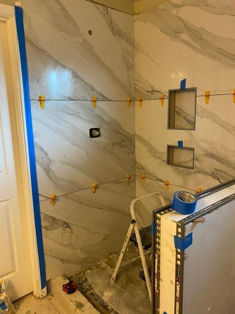 A bathroom under construction with a ladder and tape on the floor.