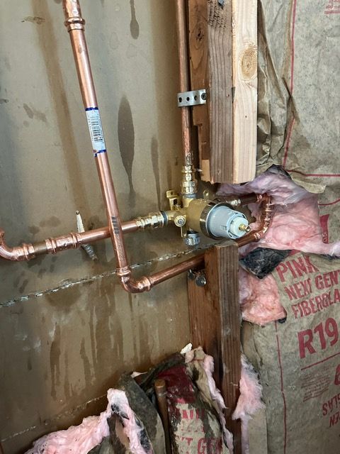 Copper pipes are being installed in a bathroom wall.