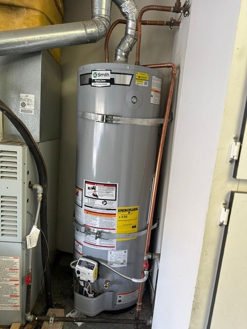 A water heater is sitting next to a furnace in a room.