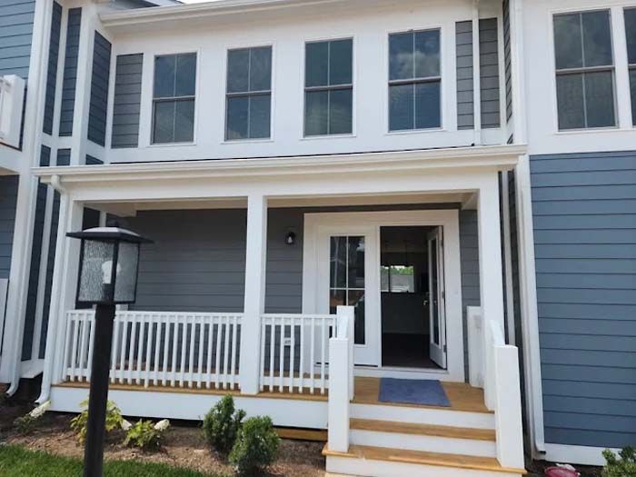 Two-story townhouse with a porch, blue siding, white trim, and a lamp post in front.