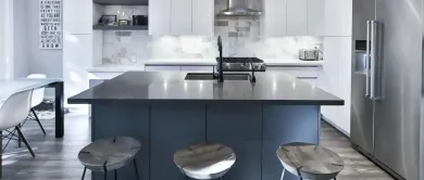 Modern kitchen with a large island, bar stools, and stainless steel refrigerator and appliances