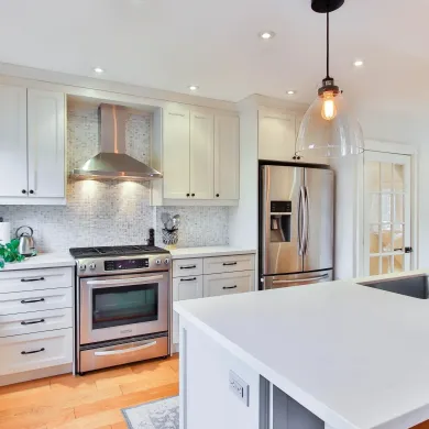 Modern white kitchen with stainless steel appliances, island, and pendant lighting