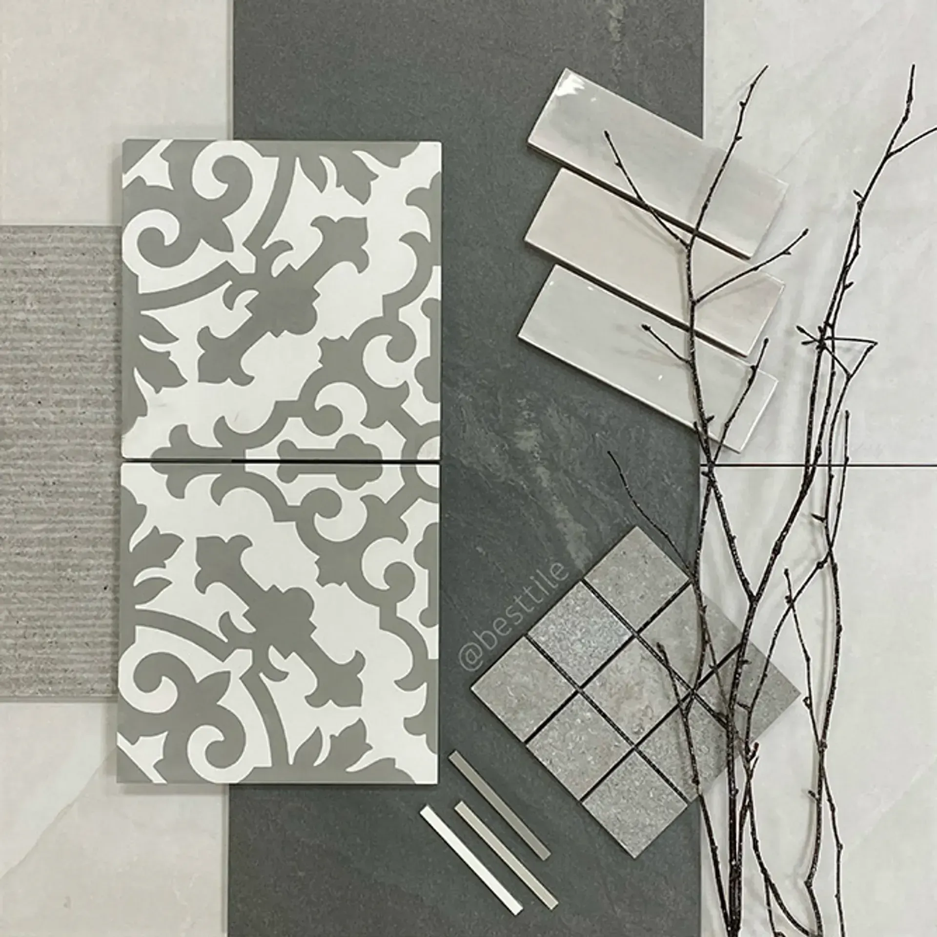 Gray patterned tiles, sample swatches, and twigs arranged on a dark surface.