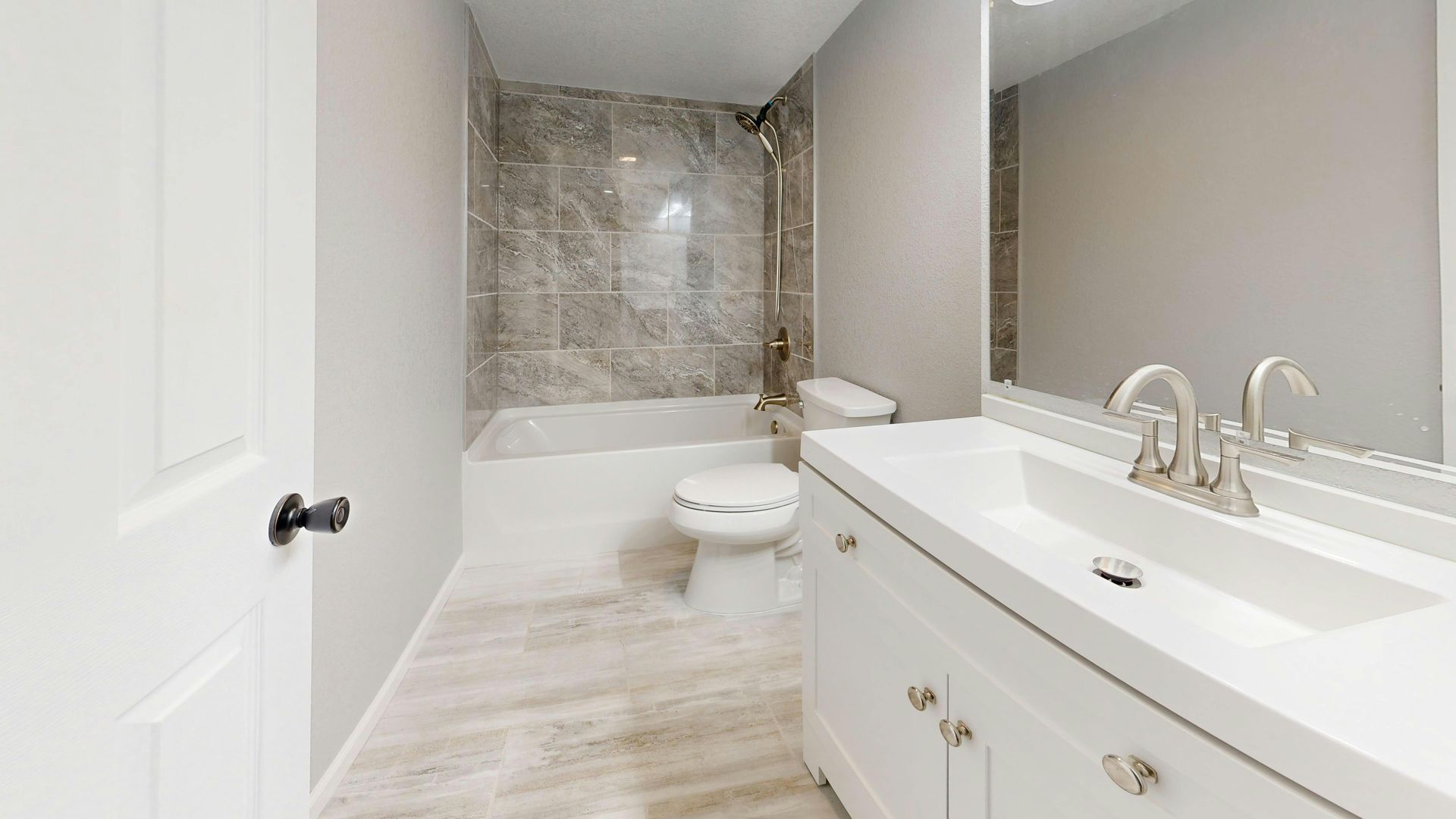 Bright bathroom with white vanity, tiled shower, and toilet under sloped ceiling