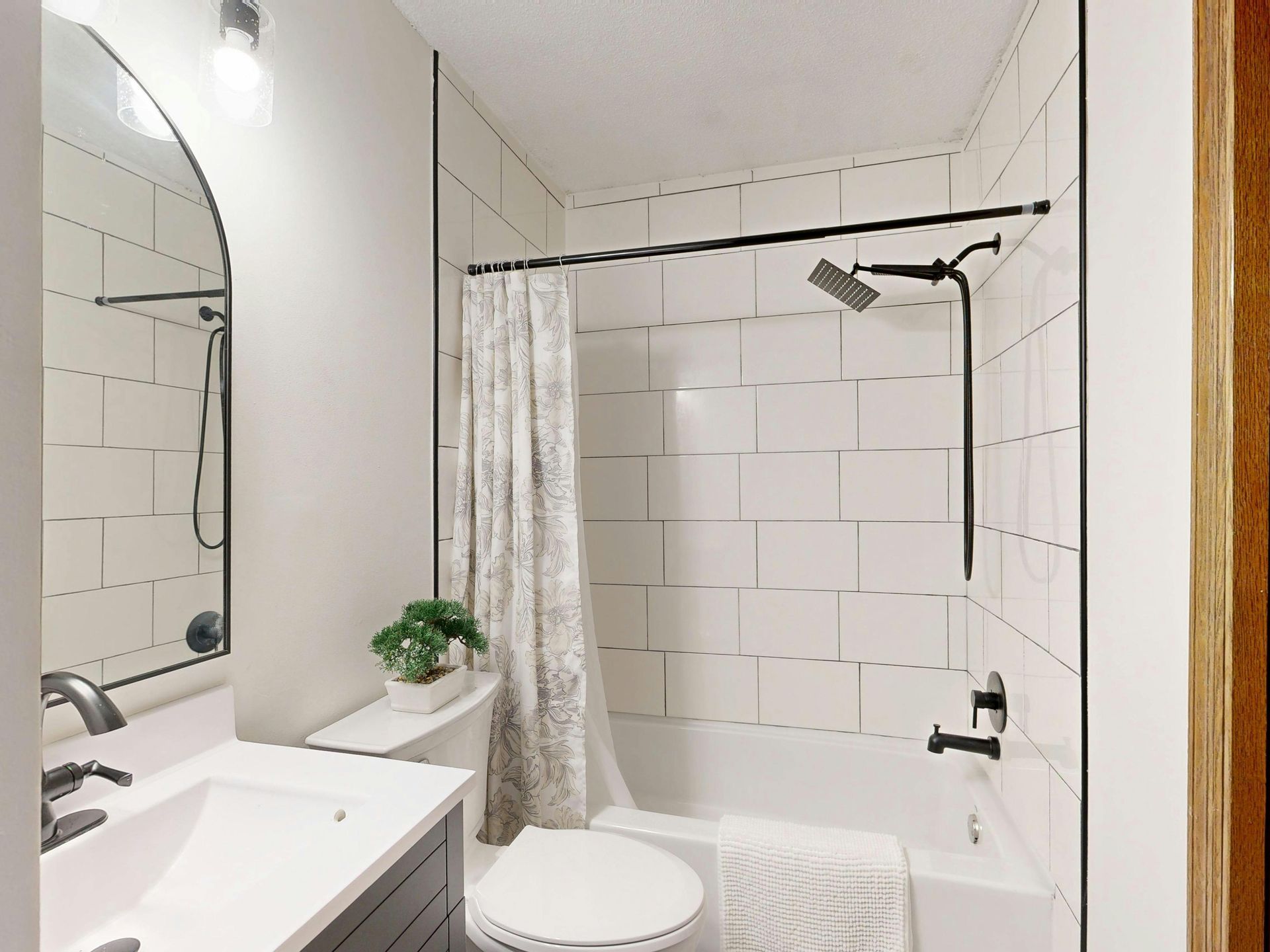 Compact white bathroom with sink, toilet, tub-shower combo, and wall-mounted showerhead