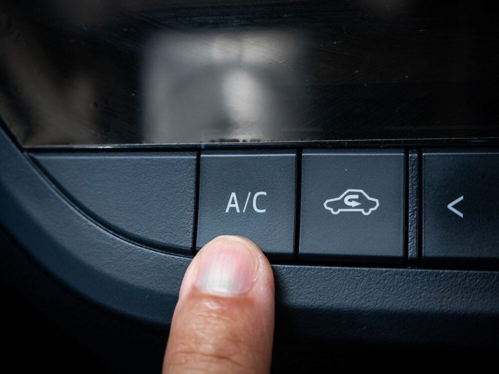 A Person is Pressing the A/C Button on a Car Dashboard — Express Auto Repairs in Ainslie, ACT