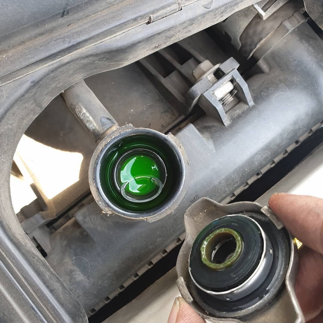 A Person is Holding a Radiator Cap With Green Liquid in It — Express Auto Repairs in Ainslie, ACT