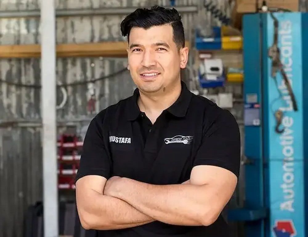 A Man in a Black Shirt is Standing With His Arms Crossed in a Garage — Express Auto Repairs in Ainslie, ACT