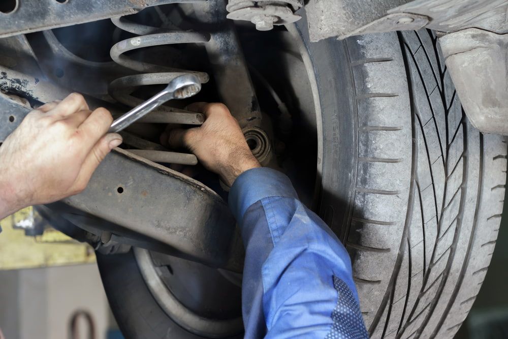 A man is working on the suspension of a car with a wrench — Express Auto Repairs in Ainslie, ACT