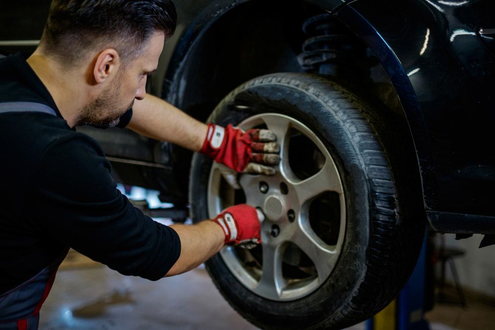 A Man is Changing a Tire on a Car in a Garage — Express Auto Repairs in Ainslie, ACT