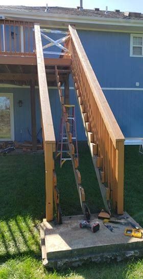 Wooden stairs leading from a deck to a concrete slab. A ladder stands inside the stairwell.