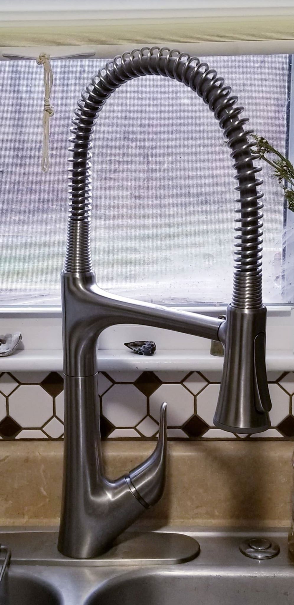 A kitchen faucet with a coiled spring arm. The faucet is silver with a modern design.