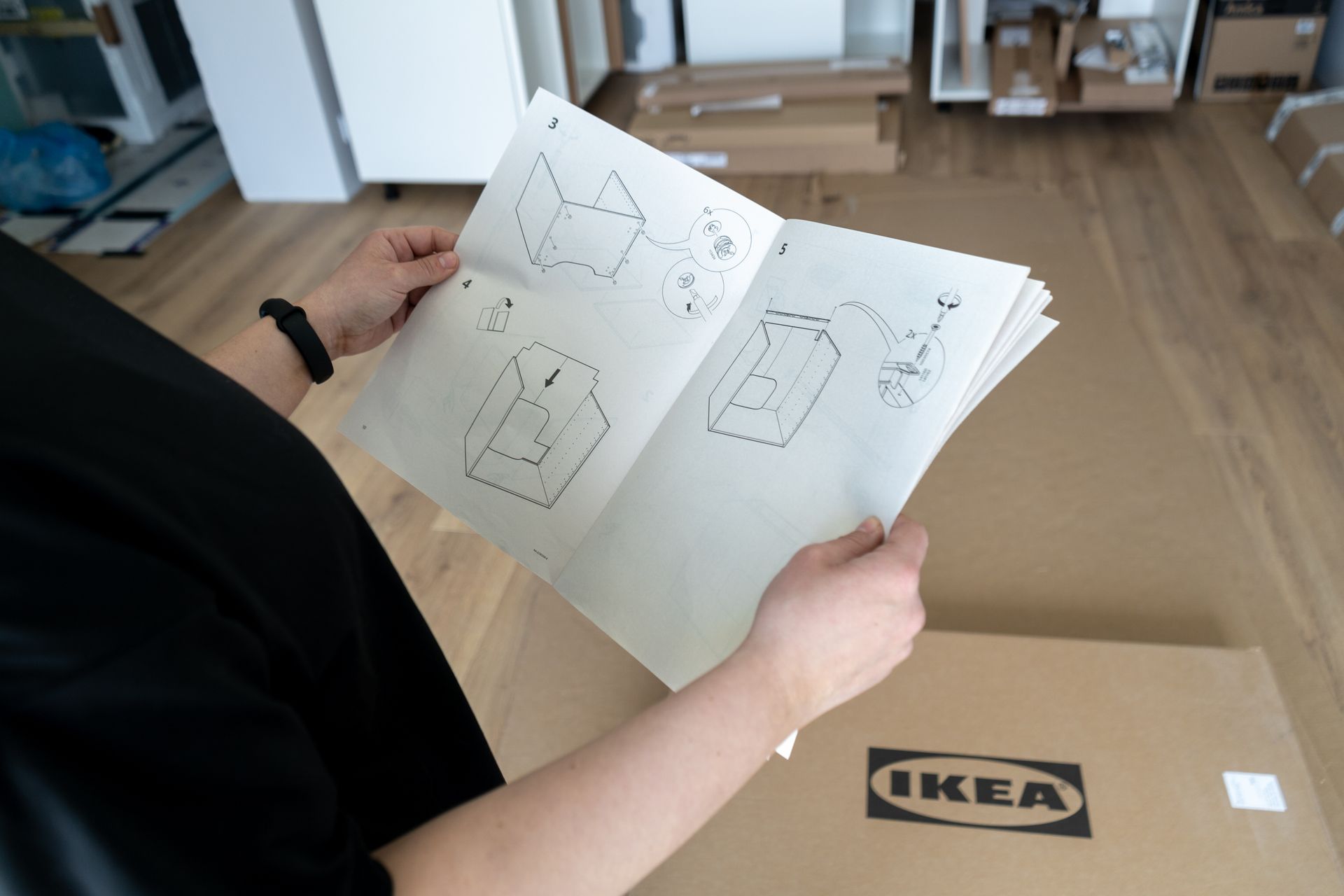 Person holding IKEA furniture assembly instructions.