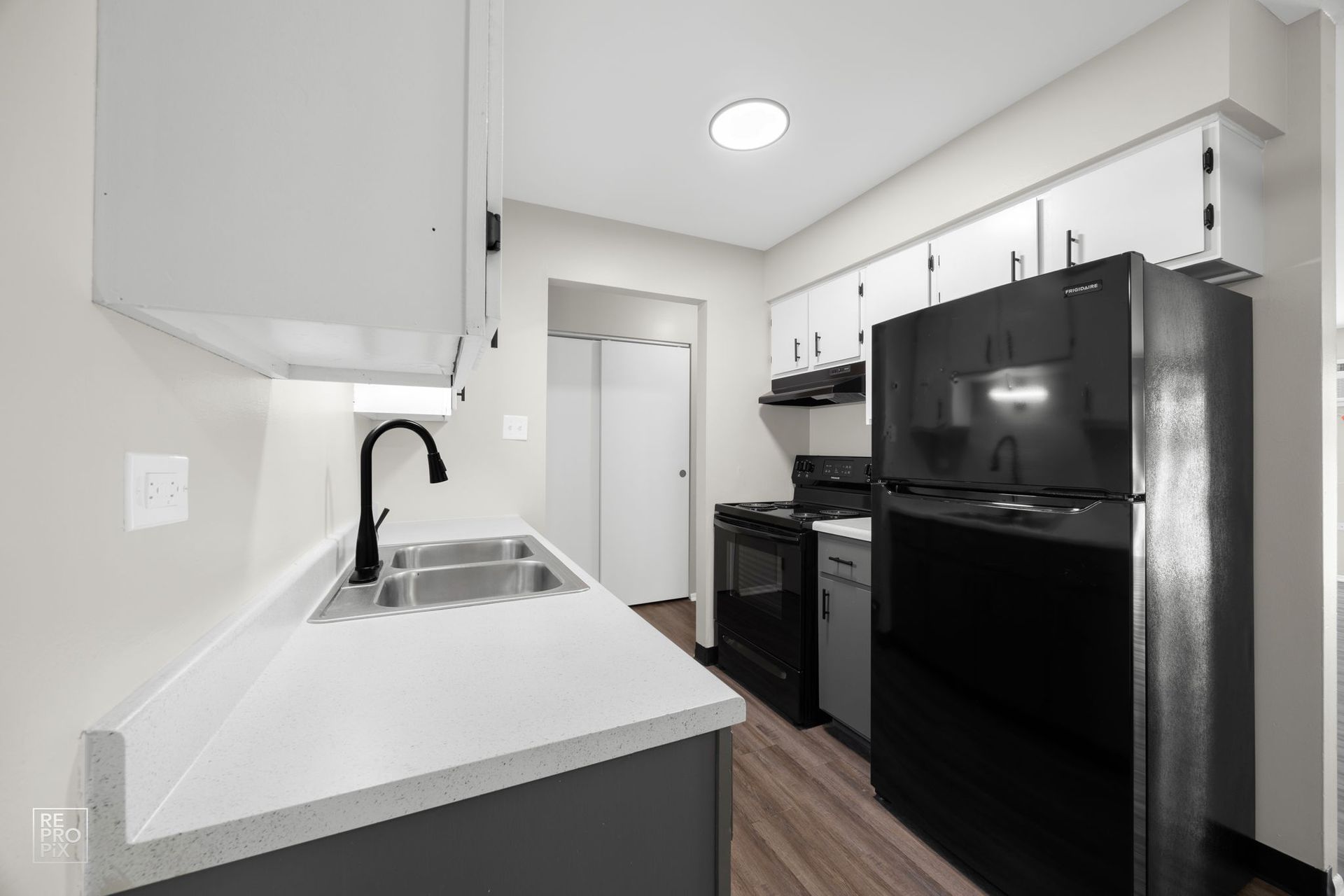 Kitchen with white countertops, black appliances, and white cabinets.