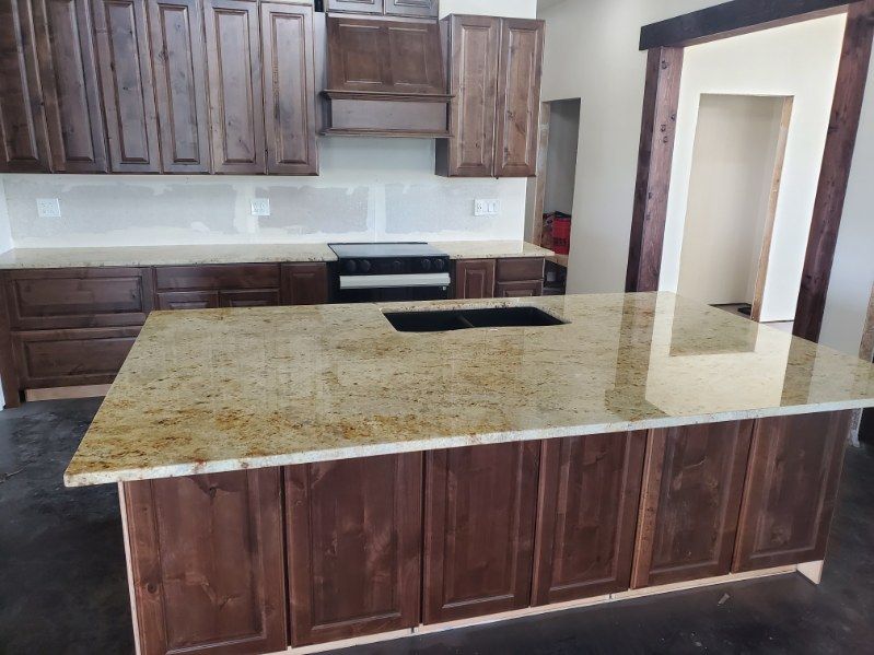 Kitchen with brown cabinets, granite countertops, and an island.