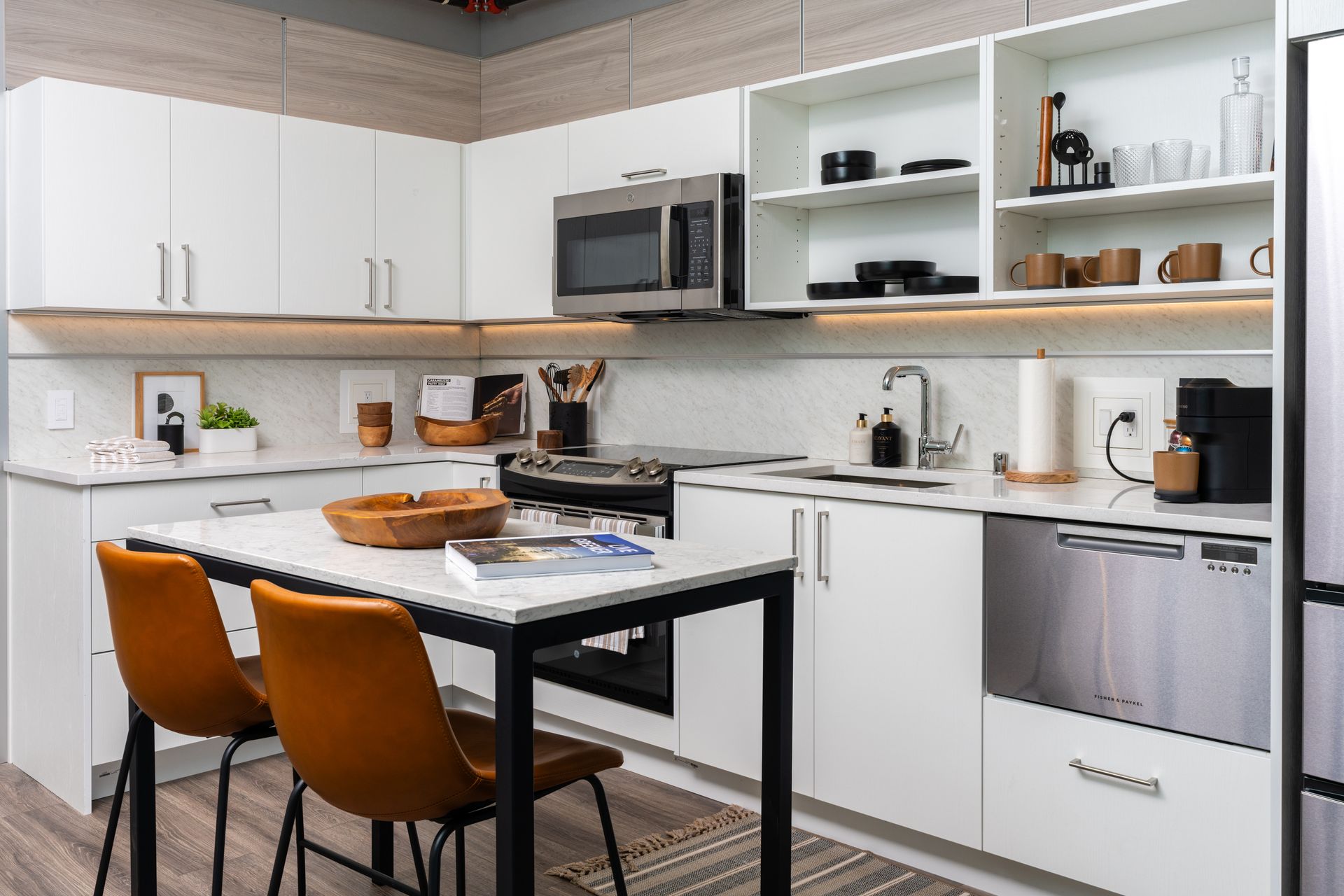 A kitchen with white cabinets, stainless steel appliances, a table, and chairs.