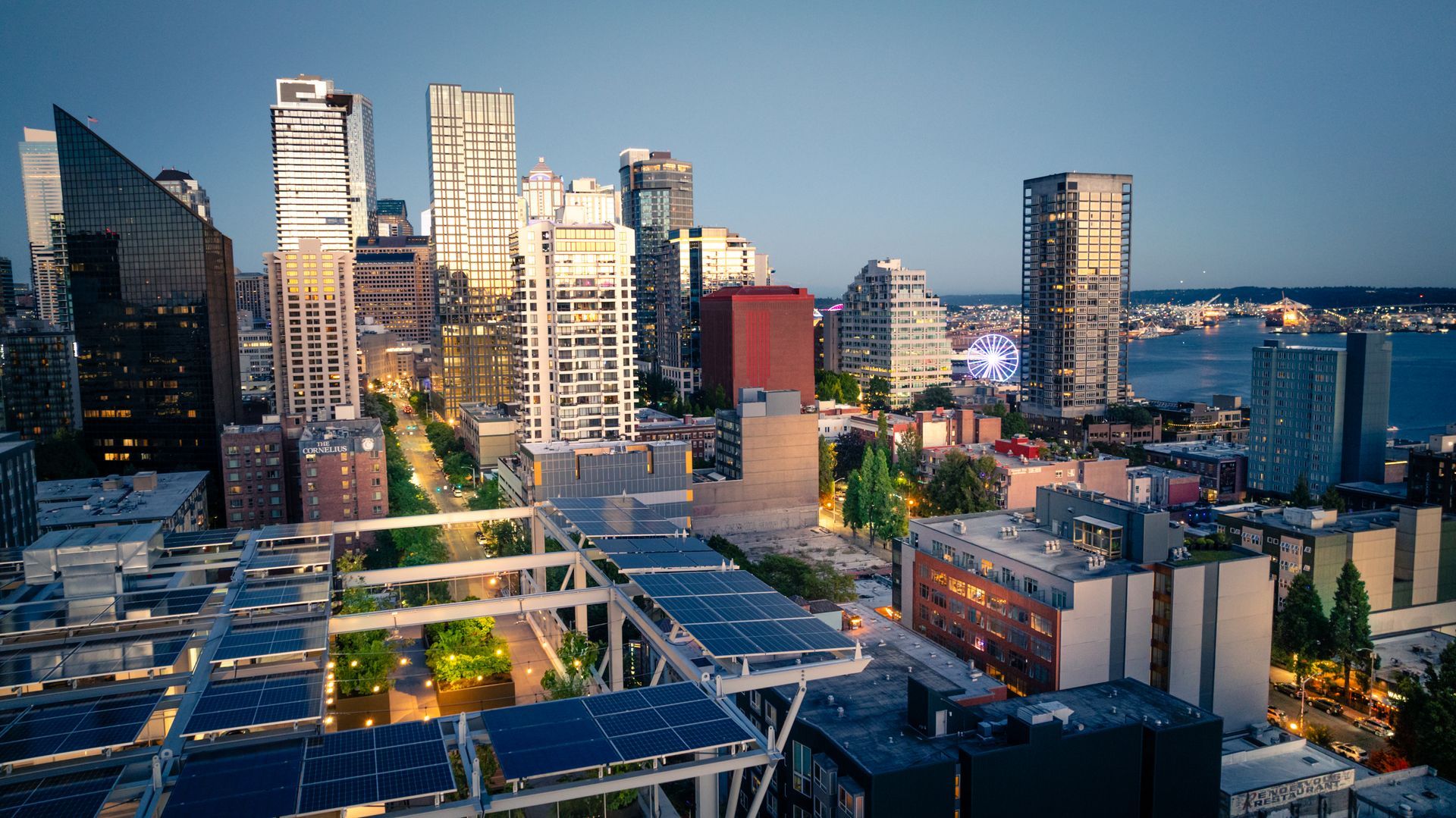 An aerial view of a city with a lot of buildings and solar panels on the roofs.