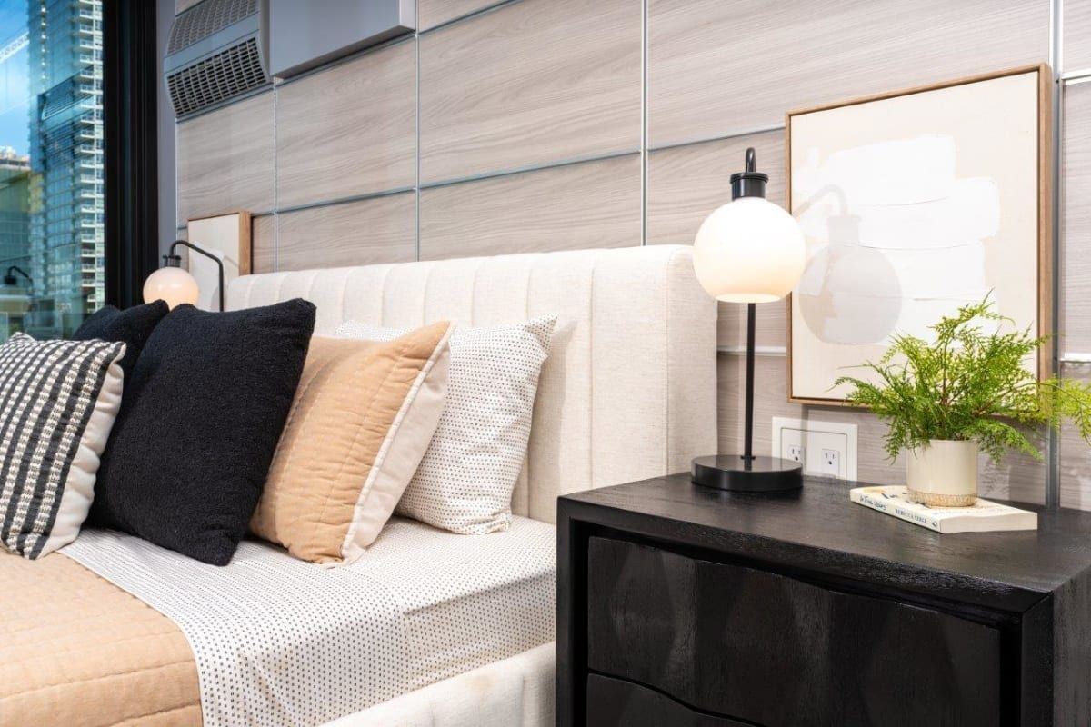 A bedroom with a bed, nightstand, lamp, and picture on the wall.