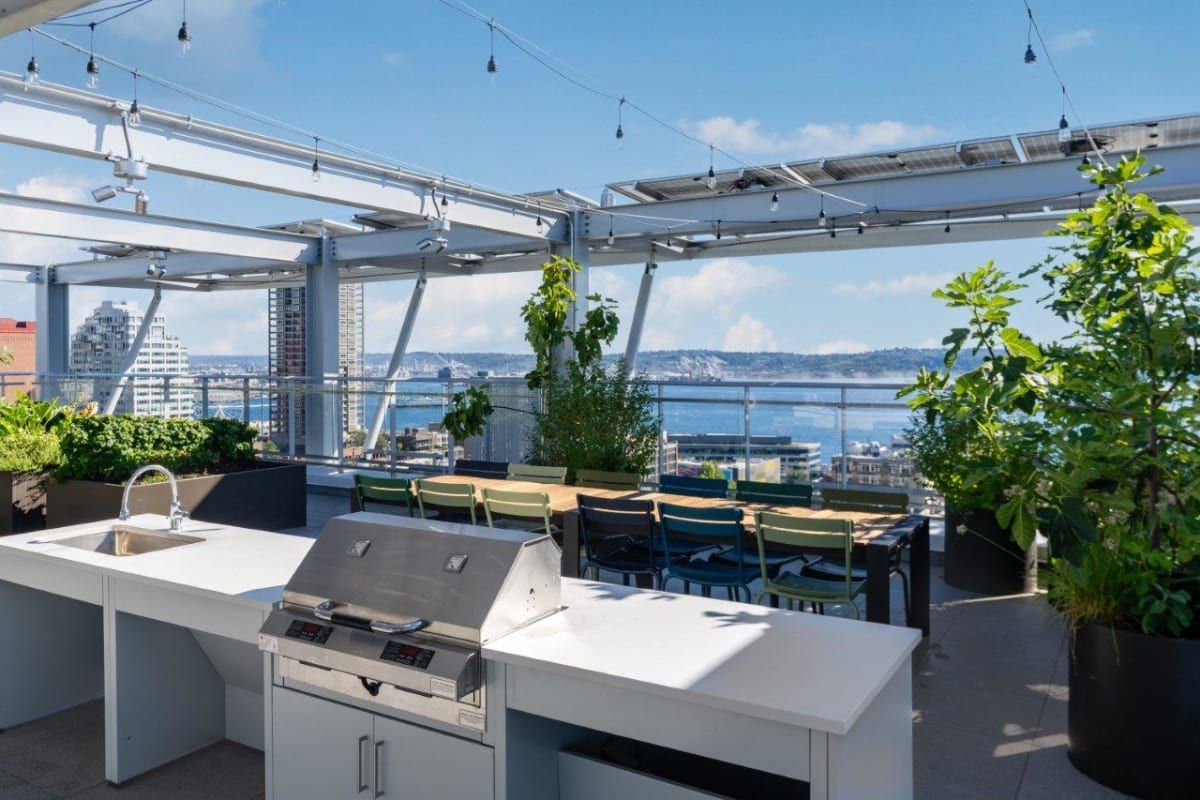 There is a grill on the roof of a building with a view of the ocean.