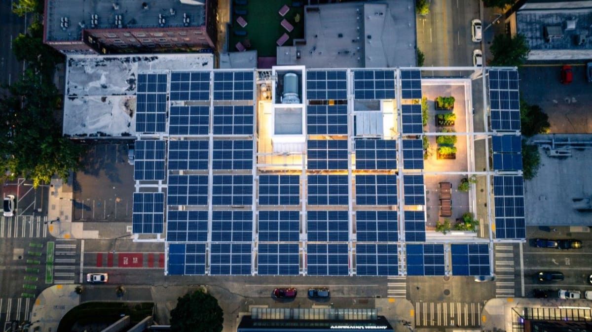 An aerial view of a building with a lot of solar panels on the roof.