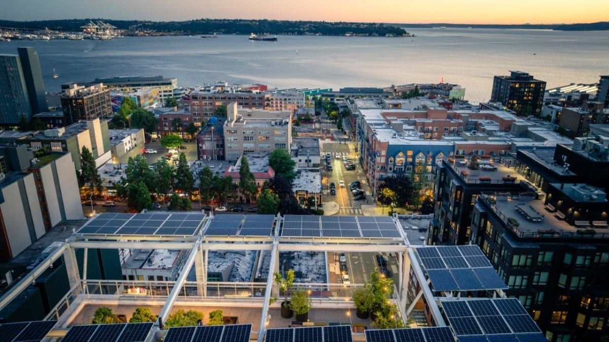 An aerial view of a city with a lot of solar panels on the roof.