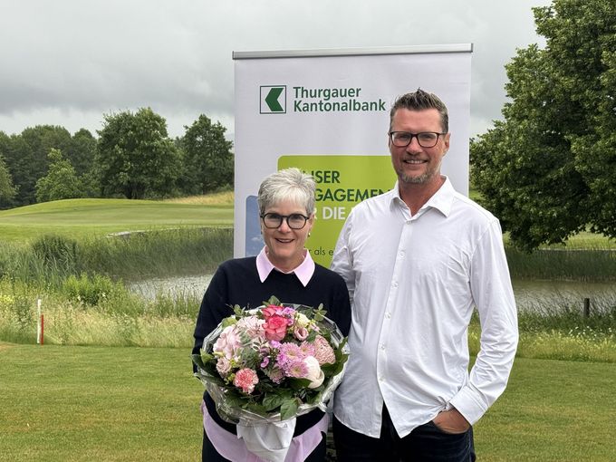 Ein Paar posiert mit einem Blumenstrauss auf einem Golfplatz.