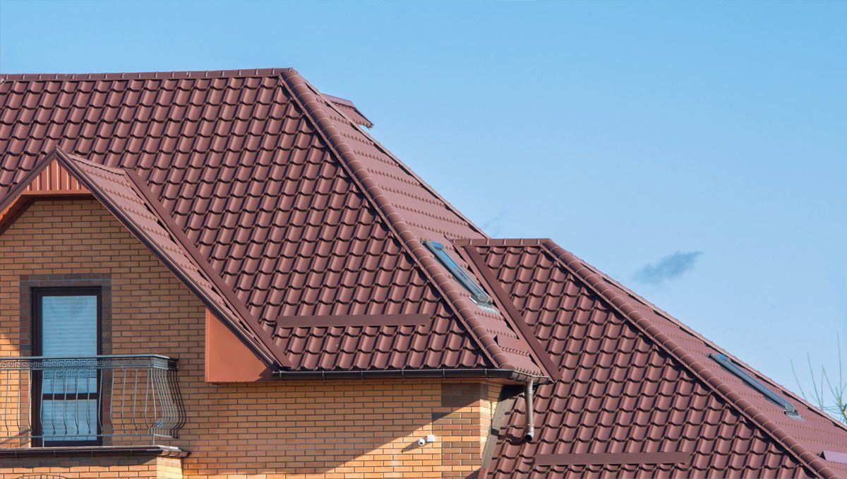 A brick house with a brown roof and a balcony.