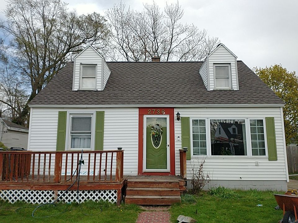 A white house with green shutters and a red door