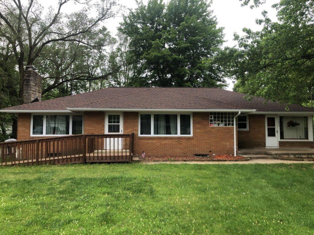 A brick house with a large lawn in front of it.